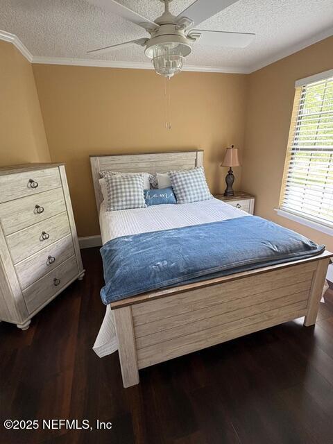 bedroom featuring crown molding, a ceiling fan, a textured ceiling, and dark wood finished floors