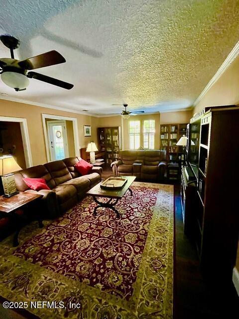 living room featuring a ceiling fan, a textured ceiling, wood finished floors, and ornamental molding