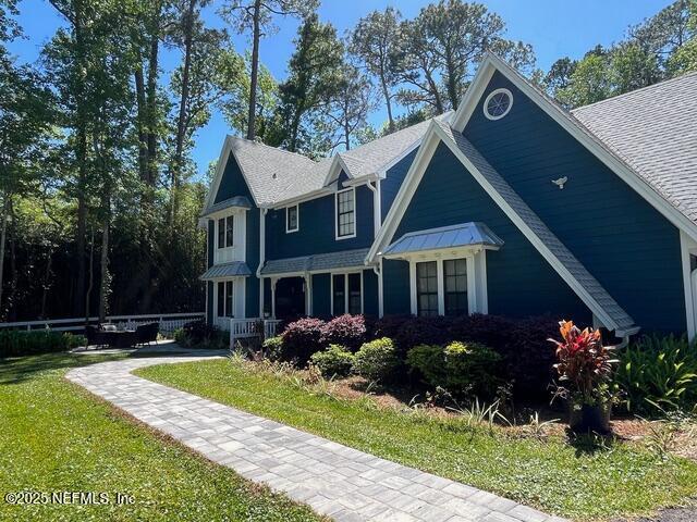 view of front facade featuring fence, a shingled roof, and a front yard