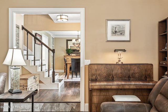 interior space featuring a notable chandelier, baseboards, wood finished floors, ornamental molding, and stairway