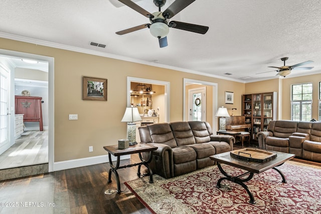 living area featuring visible vents, baseboards, ceiling fan, dark wood-style floors, and a textured ceiling