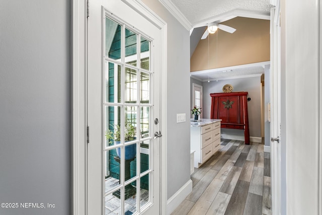 entryway with crown molding, baseboards, a textured ceiling, a ceiling fan, and light wood-style flooring