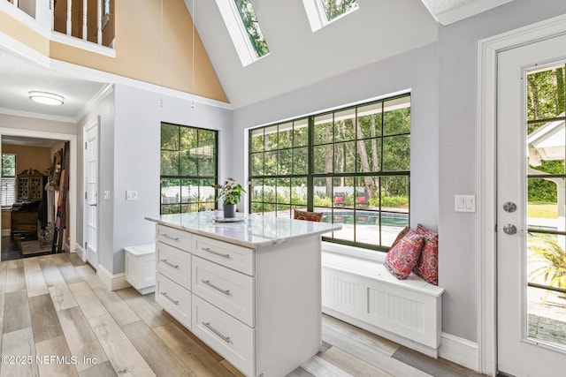 spacious closet with a skylight, high vaulted ceiling, and light wood-style floors