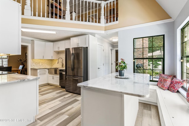kitchen featuring freestanding refrigerator, ornamental molding, a healthy amount of sunlight, and dishwasher