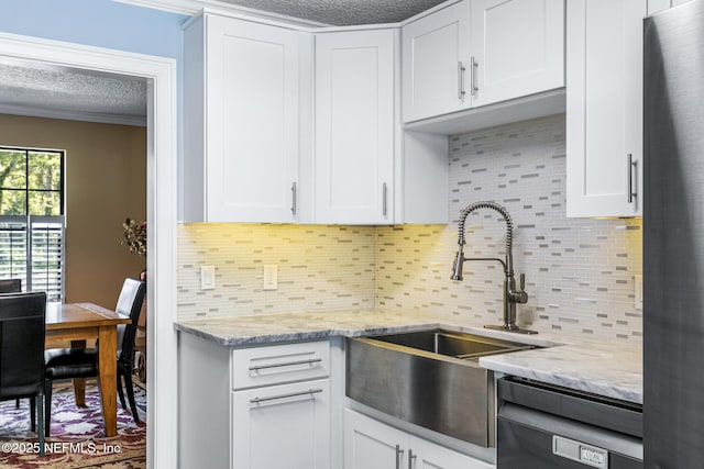 kitchen with a sink, a textured ceiling, dishwashing machine, and white cabinetry