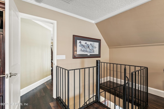 stairs with a textured ceiling, baseboards, ornamental molding, and wood finished floors