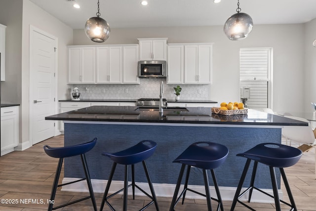 201 Bridgeton St, Saint Johns, FL 32259 - kitchen with wood finished floors, a breakfast bar area, stainless steel microwave, white cabinets, and tasteful backsplash