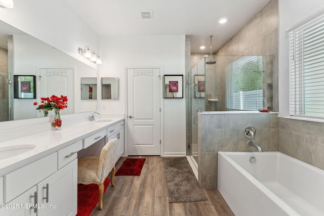 120 Oakleaf Way, Palm Coast, FL 32137 - full bath featuring a sink, double vanity, wood finished floors, a garden tub, and a stall shower