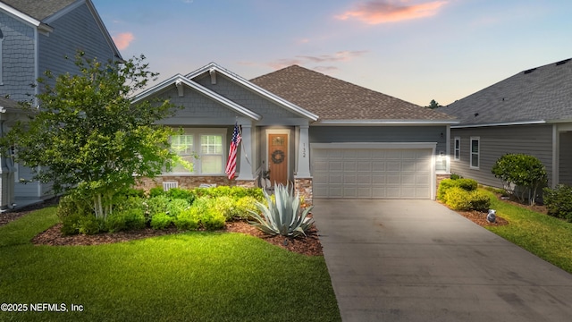 view of front of property featuring an attached garage, driveway, a yard, and stone siding