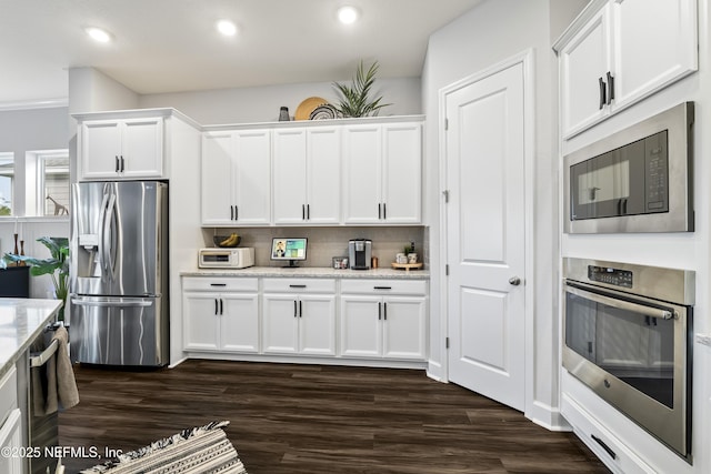 kitchen featuring appliances with stainless steel finishes, white cabinetry, dark wood-style floors, light stone countertops, and recessed lighting