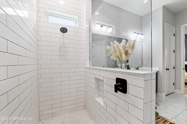 ensuite bathroom with a tile shower, marble finish flooring, and vanity