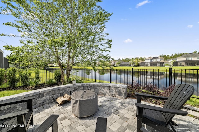 view of patio / terrace featuring a water view, an outdoor fire pit, a fenced backyard, and a residential view