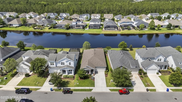 aerial view of residential area featuring a nearby body of water and a heavily wooded area