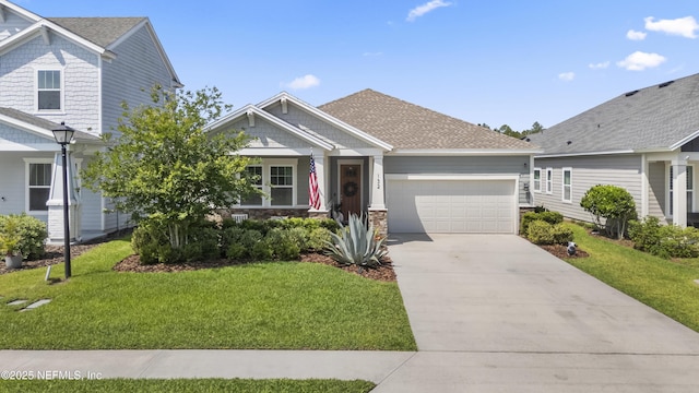 craftsman house featuring an attached garage, a front yard, driveway, stone siding, and roof with shingles
