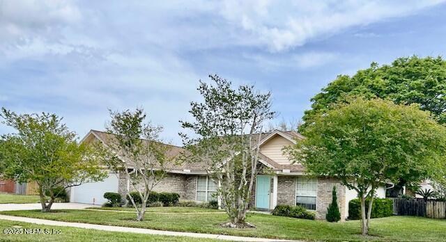 view of front of property with an attached garage, fence, concrete driveway, a front lawn, and brick siding