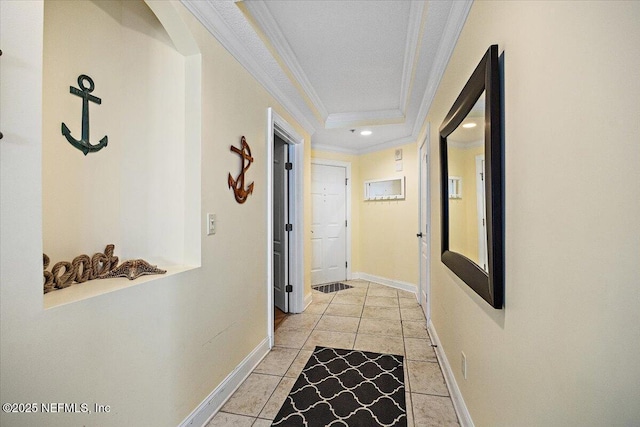 hallway with crown molding, baseboards, recessed lighting, light tile patterned floors, and a tray ceiling
