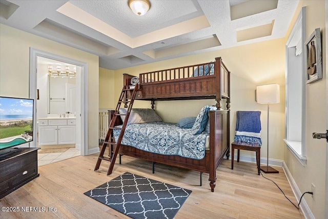 bedroom featuring coffered ceiling, light wood-style flooring, beamed ceiling, baseboards, and ensuite bathroom