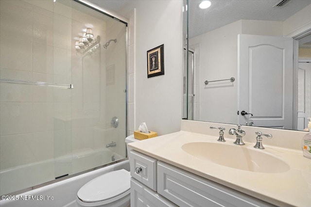 bathroom featuring toilet, shower / bath combination with glass door, vanity, and a textured ceiling
