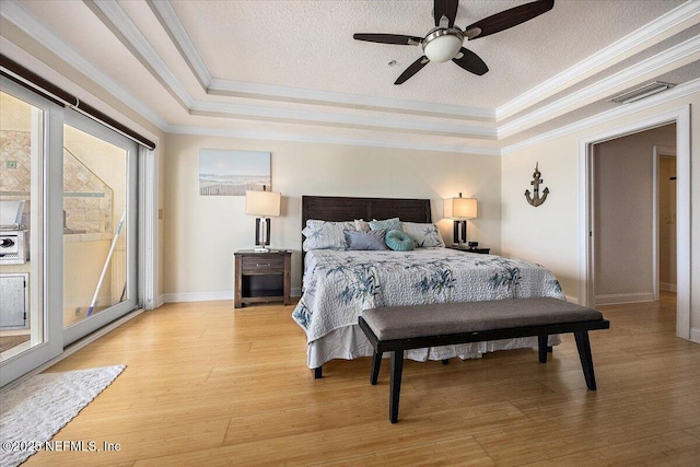 bedroom with crown molding, a raised ceiling, light wood-style flooring, access to exterior, and a textured ceiling