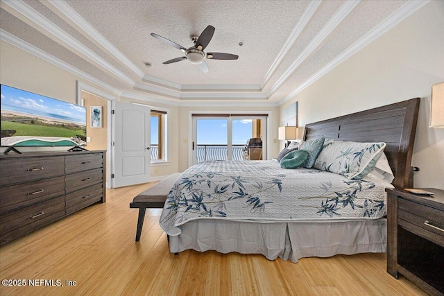 bedroom with a tray ceiling, access to exterior, light wood finished floors, ornamental molding, and ceiling fan