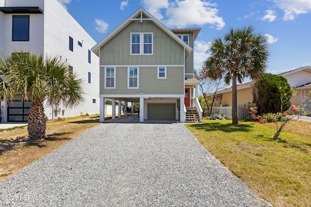raised beach house with a garage, board and batten siding, stairway, a carport, and driveway