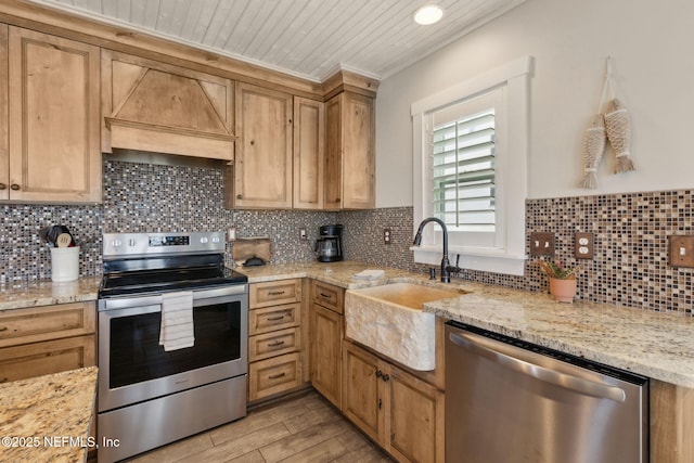 kitchen with wall chimney range hood, wood ceiling, tasteful backsplash, a sink, and appliances with stainless steel finishes