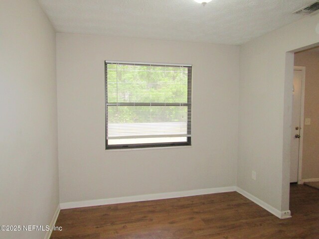 spare room featuring baseboards, visible vents, and wood finished floors