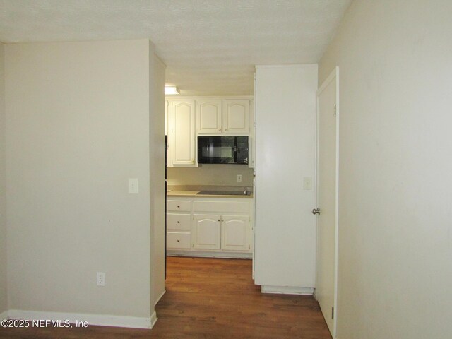 kitchen with light countertops, white cabinets, wood finished floors, and black appliances