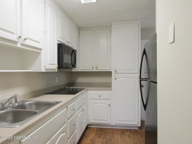 kitchen featuring dark wood-style flooring, a sink, light countertops, white cabinetry, and black appliances