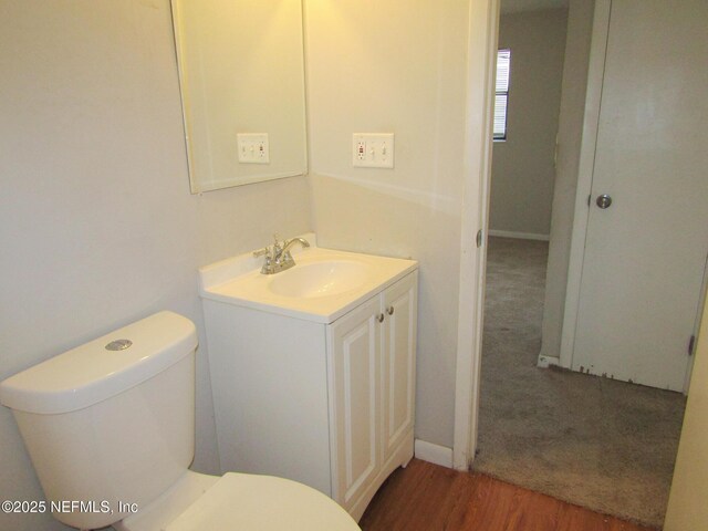 bathroom featuring toilet, wood finished floors, and vanity
