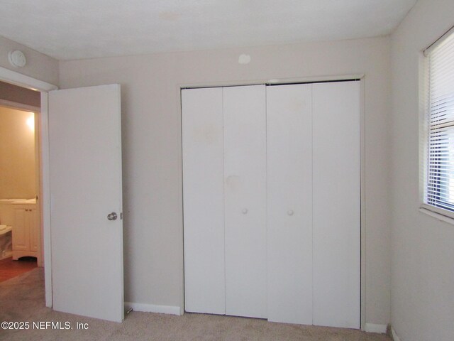 unfurnished bedroom featuring a closet, baseboards, and light carpet