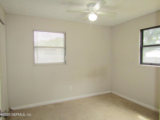 empty room featuring a ceiling fan, baseboards, and light colored carpet
