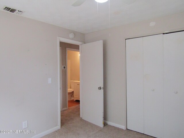 unfurnished bedroom featuring a ceiling fan, visible vents, baseboards, a closet, and light carpet