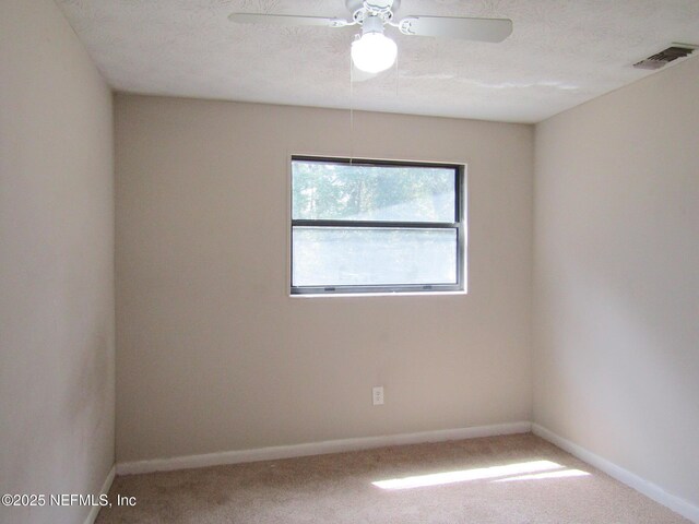 carpeted empty room featuring a ceiling fan, baseboards, and visible vents
