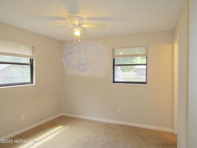unfurnished room featuring light colored carpet, a ceiling fan, and baseboards