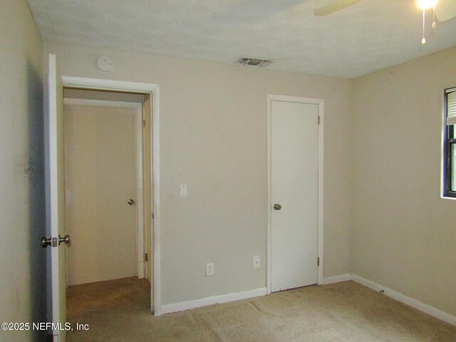 unfurnished bedroom featuring baseboards, carpet, and visible vents