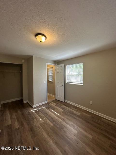 3262 Dignan St, Jacksonville, FL 32254 - unfurnished bedroom with baseboards, a closet, dark wood-style flooring, and a textured ceiling