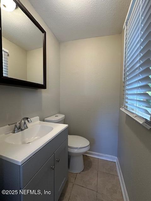 3262 Dignan St, Jacksonville, FL 32254 - bathroom with a textured ceiling, baseboards, tile patterned floors, vanity, and toilet