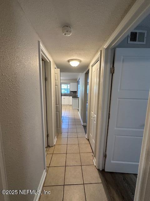 3262 Dignan St, Jacksonville, FL 32254 - hallway with baseboards, a textured ceiling, visible vents, and light tile patterned floors