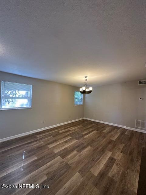 3262 Dignan St, Jacksonville, FL 32254 - unfurnished room featuring visible vents, baseboards, dark wood-style floors, and an inviting chandelier