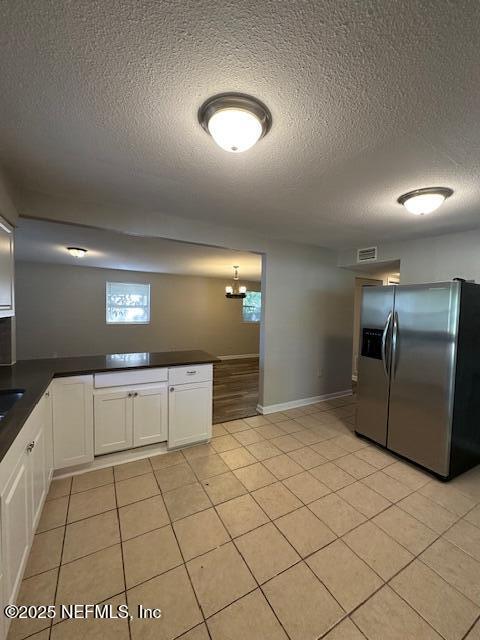 3262 Dignan St, Jacksonville, FL 32254 - kitchen with white cabinets, a textured ceiling, dark countertops, and stainless steel fridge with ice dispenser