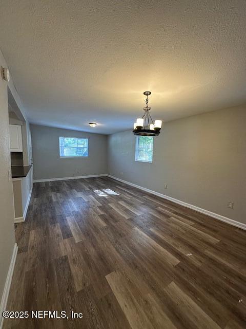 3262 Dignan St, Jacksonville, FL 32254 - unfurnished dining area featuring baseboards, a textured ceiling, dark wood-style flooring, and a notable chandelier