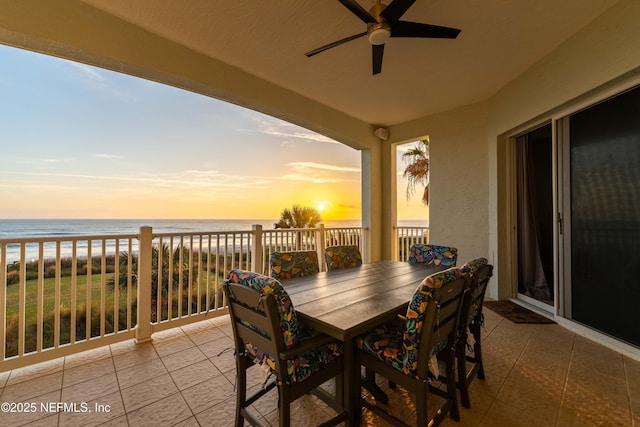 view of patio featuring view of water and beach, a ceiling fan, and outdoor dining area