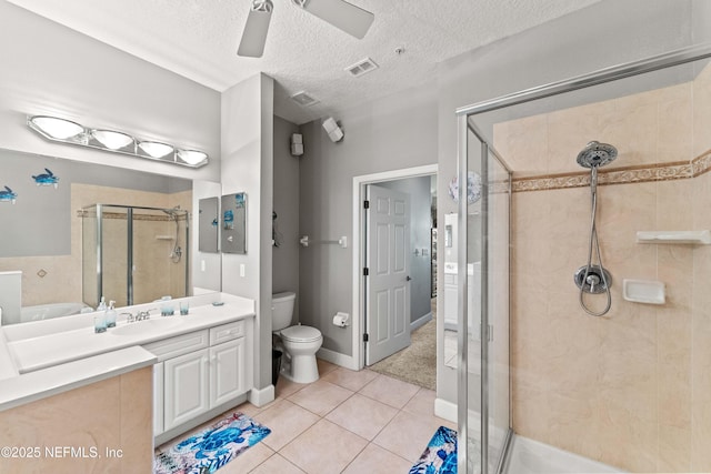 bathroom featuring a stall shower, toilet, ceiling fan, tile patterned flooring, and vanity