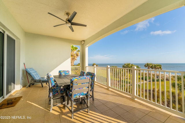 balcony with a water view, outdoor dining space, and ceiling fan