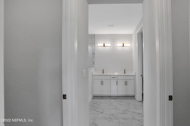 bathroom with a sink, double vanity, and marble finish floor