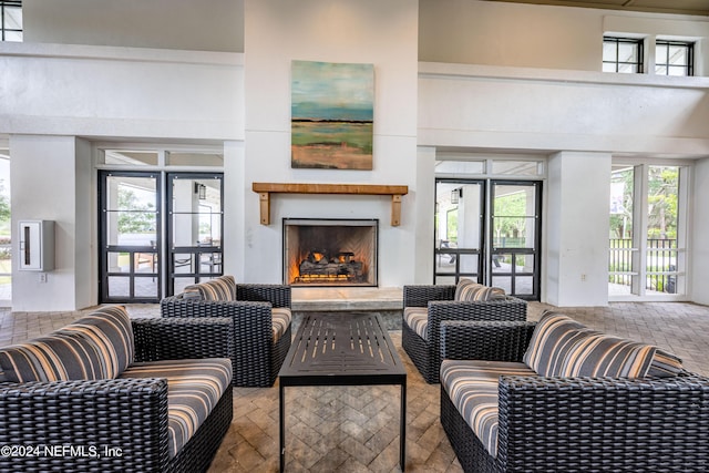 living room featuring plenty of natural light, brick floor, and a warm lit fireplace