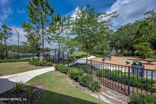 view of property's community with a lawn, a water view, fence, and playground community