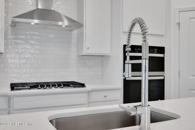 37 Bird Watch Ct, Saint Augustine, FL 32092 - kitchen with wall chimney exhaust hood, stainless steel gas stovetop, decorative backsplash, white cabinets, and light stone countertops