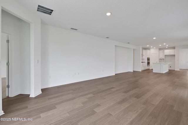 37 Bird Watch Ct, Saint Augustine, FL 32092 - unfurnished living room featuring light wood-style flooring, recessed lighting, baseboards, and a sink